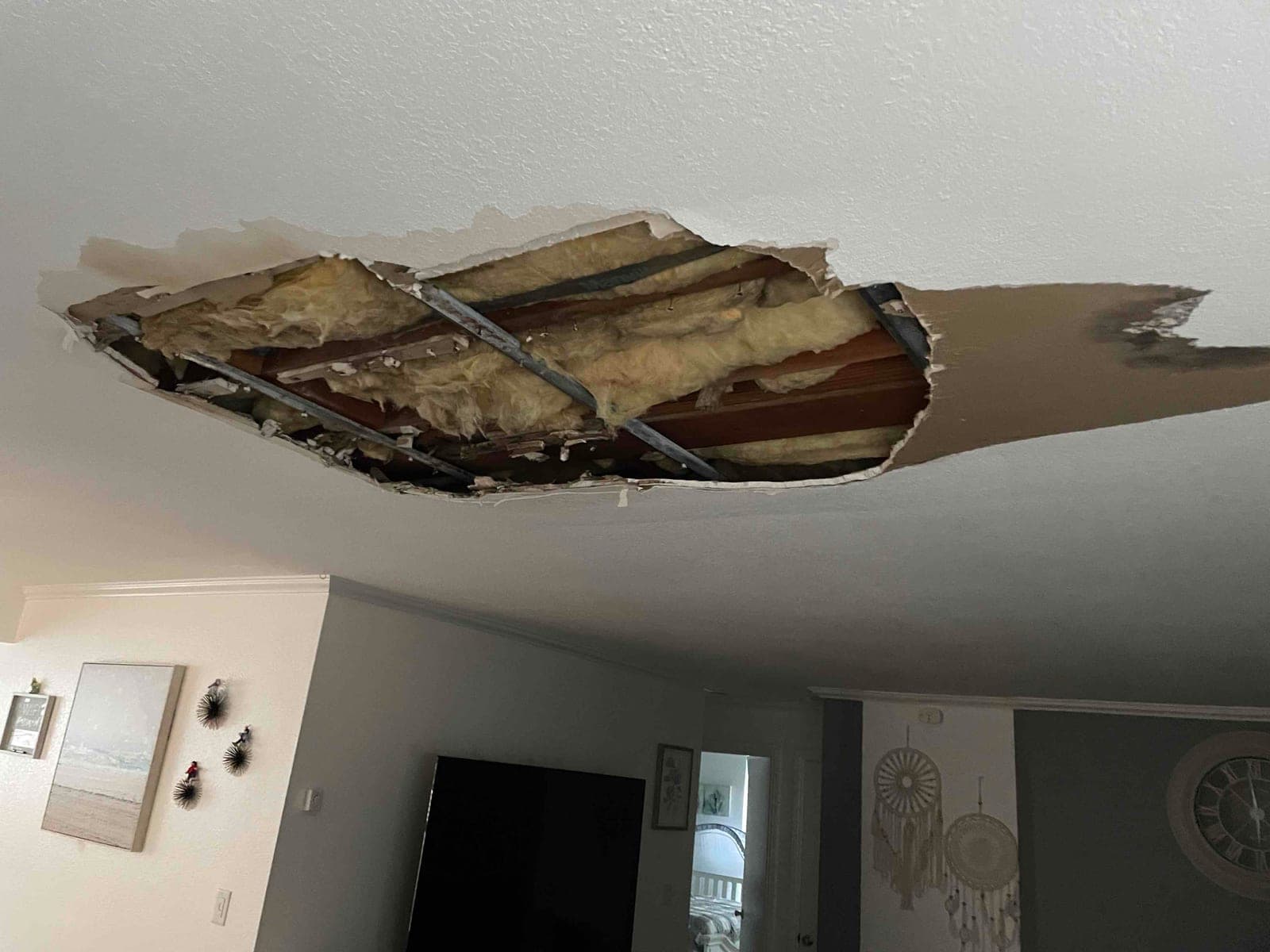 Before photo of a large irregular ceiling opening exposing framing and insulation.