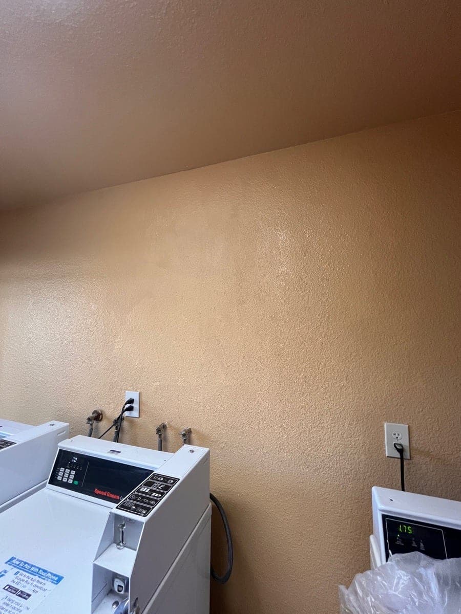 After photo of the same laundry wall repaired with orange peel texture and paint.